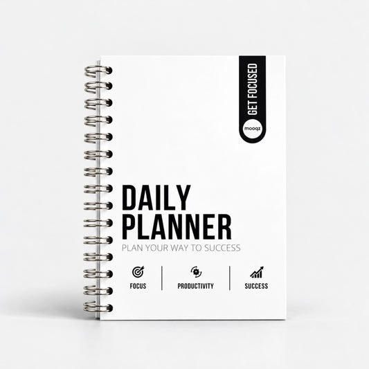 Witte Mooqz Daily Planner met zilverkleurige metalen spiraalbinding, zwart Get Focused-label en de tekst Plan Your Way to Success op de cover.